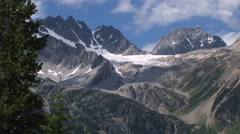 Mountain glacier framed by trees against a brilliant blue sky. Stock Footage 52221257