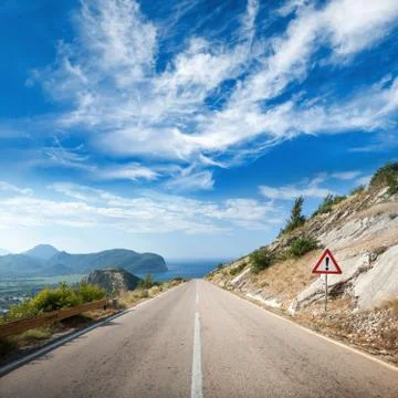 Mountain highway perspective with dramatic cloudy sky and exclamation mark ro Stock Photos