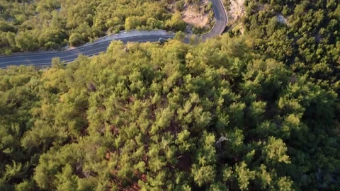 Mountain highway with sharp turns beside steep cliff and dense forest at dusk 스톡 동영상 326353312