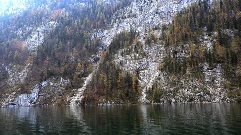 Mountain lake is surrounded by autumn forest Stockbeeldmateriaal 98021185