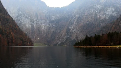 Mountain lake is surrounded by autumn forest Stock Footage 98320416