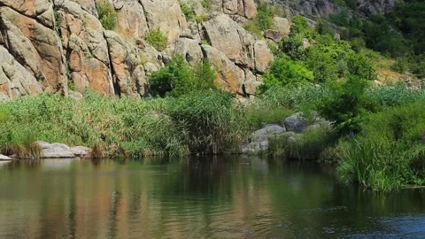 Mountain lake surrounded by stone rocks and green leaves of reeds. Stock Footage 169938542
