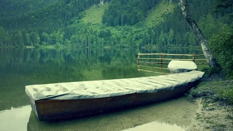Mountain lake with wooden rustic rowing boat, evening peaceful atmosphere. Stock Footage 78551321
