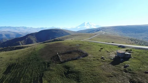 Mountain landscape from above: snow-capped peaks, a small house and a corral for Stock Footage 117769823