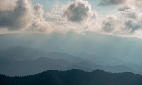 Mountain landscape with bright sun rays shining and cloudy sky in the morning. Photos