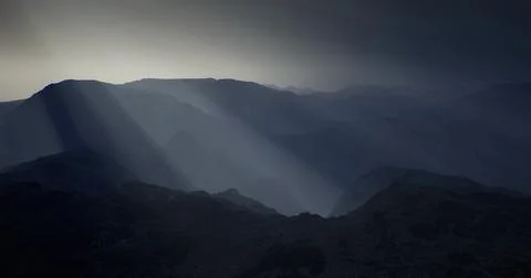 Mountain landscape with dramatic light shining through clouds during dusk Stock Illustration