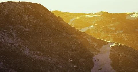 Mountain landscape during sunset with golden hues reflecting off rocks Stock Illustration