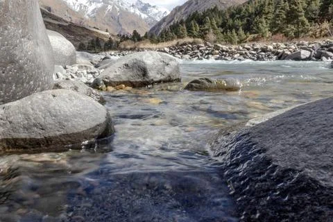 Mountain landscape featuring a clear river flowing through rocky terrain wi.. Stock Photos