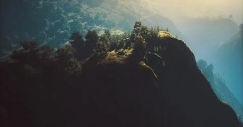 Mountain landscape featuring trees and sunlight at dawn in a distant valley Stock Illustration