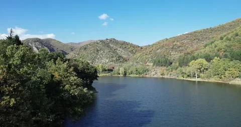 Mountain landscape flight over calm lake water on spring sunny day Stock Footage 310336643