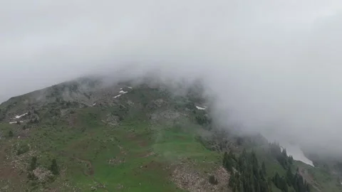 Mountain landscape with fog rolling over green hills and rocky terrain Stock Footage 336964907