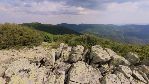 Mountain landscape with large moss-covered rocks and green forested hills in the Stock Footage 319003079