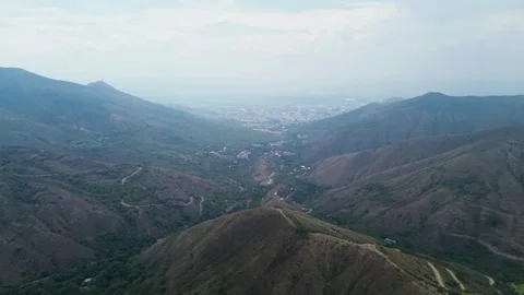 Mountain landscape opening to city view, Drone footage from rural hills to Stock Footage 319860713