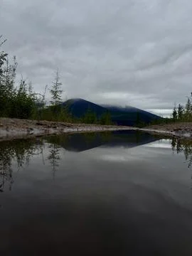 Mountain landscape with reflection in a puddle under cloudy sky Photos