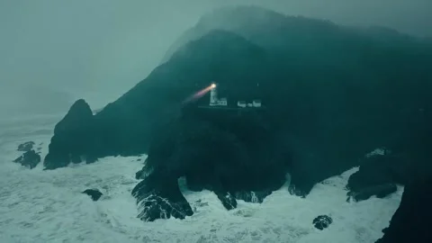 Mountain Lighthouse Beam Sweeping Over Choppy Sea at Dusk Video stock 315099139