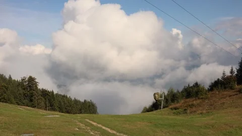 Mountain meadow opens to dramatic sky with massive white clouds rolling above da Stock Footage 318219838