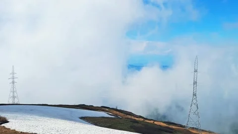 Mountain pass with snow patch under thick thick clouds and high voltage tower Stock Footage 336707940