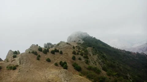 Mountain pass, windy, near the clouds, fog flows into the green valley over the Stock Footage 223048342
