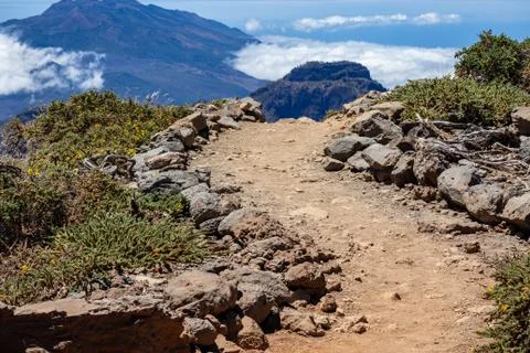 Mountain path close up leading to a cliff. Background volcano and blue clouds Foto stock