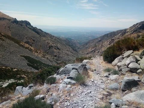 A mountain path descending through a rocky valley Stock Photos