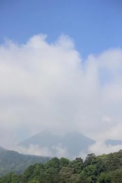 Mountain Peak Covered by Clouds Under Clear Blue Sky Stock Photos