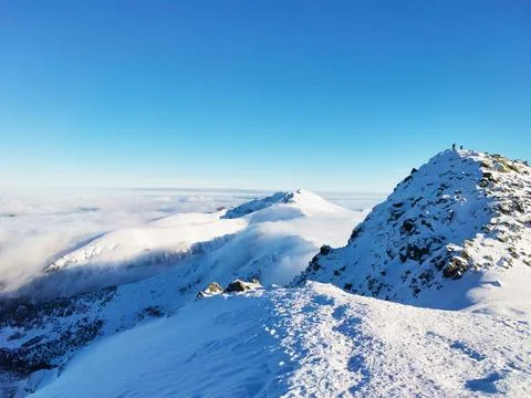 Mountain peak covered with snow surrounded by clouds Stock Photos