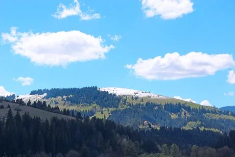 Mountain peak covered with snow under bright blue sky with clouds Stock Photos