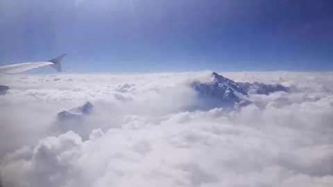 Mountain peak emerge from the cloud. A view from aeroplane's window. Stock Photos