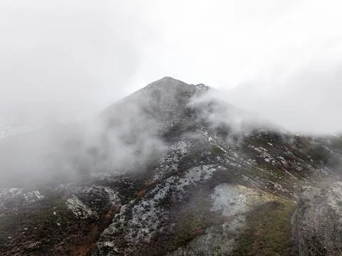 Mountain peak emerging through heavy fog and clouds Stock Photos