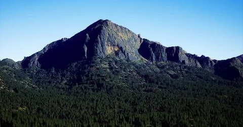 Mountain peak rises above dense forest under a clear blue sky Stock Illustration