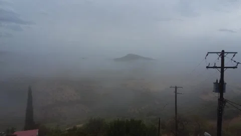 Mountain peak rising above dense fog covering wide rural plain landscape Stock Footage 344094715