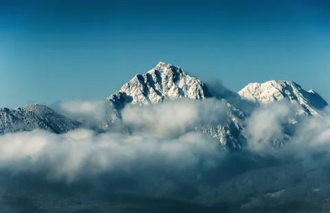 Mountain peak with snow in cloud on blue sky background, travel destination Stock Photos