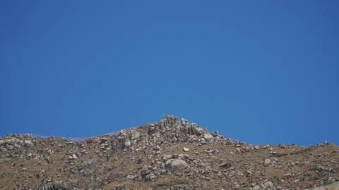 Mountain peak with some clouds and clear blue sky Stock Photos