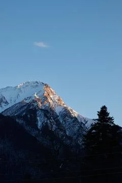 Mountain peak at sunset, part of mountain is illuminated by rays of sun, clear Stock Photos