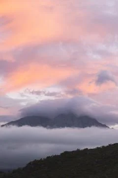 Mountain peaking out of the clouds Stock Photos