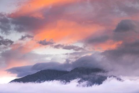 Mountain peaking out of the clouds Stock Photos