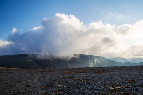 Mountain peaks in the clouds. A chain of gray mountains in the backlight Stock Photos