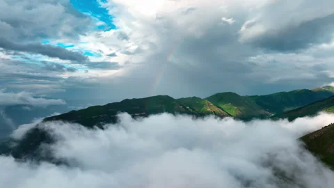 Mountain Peaks Emerging from Clouds with Rainbow. Mountain Peaks Emerging from Stock Footage 265037724
