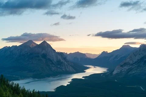 Mountain peaks frame a reflective lake at sunrise, creating a serene vista. Stock Photos