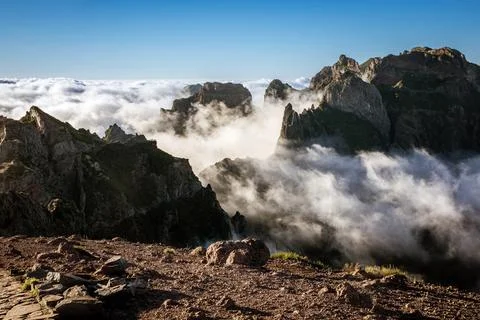 Mountain pinnacles at sunset. Clouds below the peaks. Stock Photos