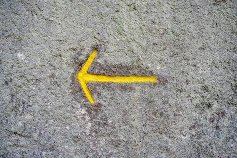 Mountain pointer on yellow arrow on a stone close-up, direction backward t... Foto stock
