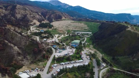 Mountain quarry or mining site with industrial buildings and trucks parked Stock Footage 344094783
