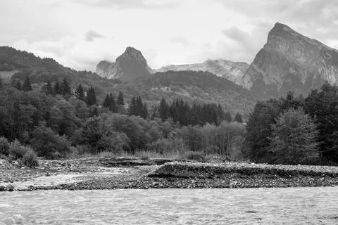 Mountain range above a forest a river in a beautiful dramatic landscape Stock Photos