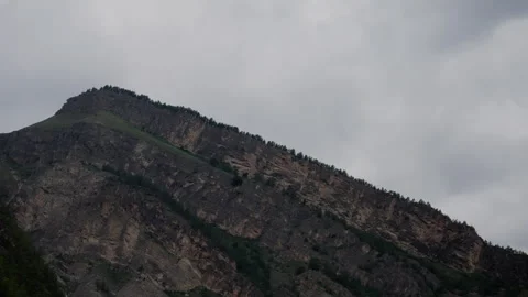 A mountain range against the background of a cloudy and gray sky. Shooting of Stock Footage 260785548