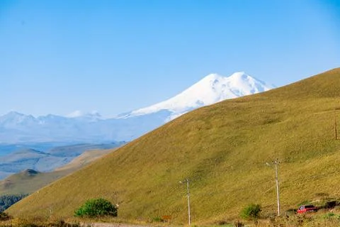 A mountain range and Mount Elbrus with a snow covered peak and a green valley Stock Photos
