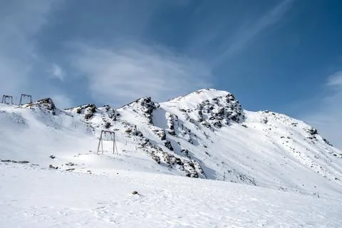Mountain range and snow-capped rocky peaks with supports for cable car Stock Photos