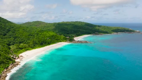 Mountain range and tropical beach with vibrant turquoise waters. La Digue Stock Footage 303633830