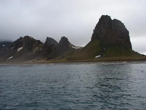A mountain range is in the background of a body of water Stock Photos