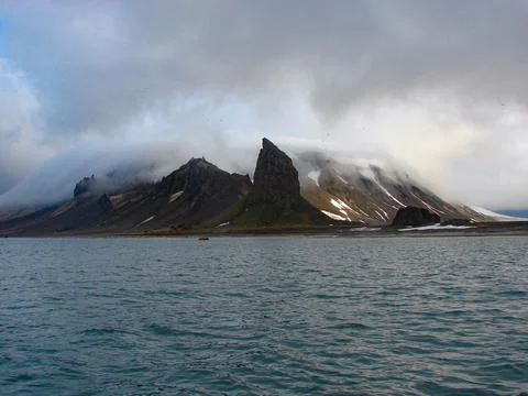 A mountain range is in the background of a body of water Stock Photos