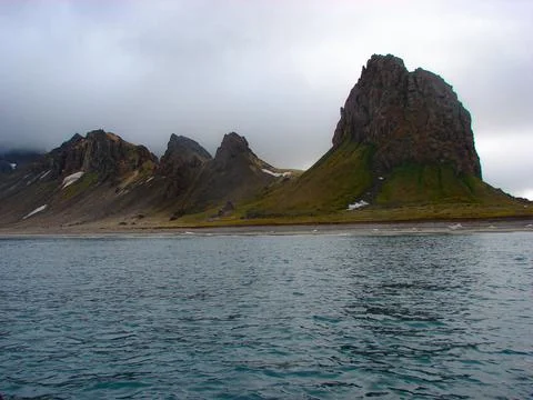 A mountain range is in the background of a body of water Stock Photos